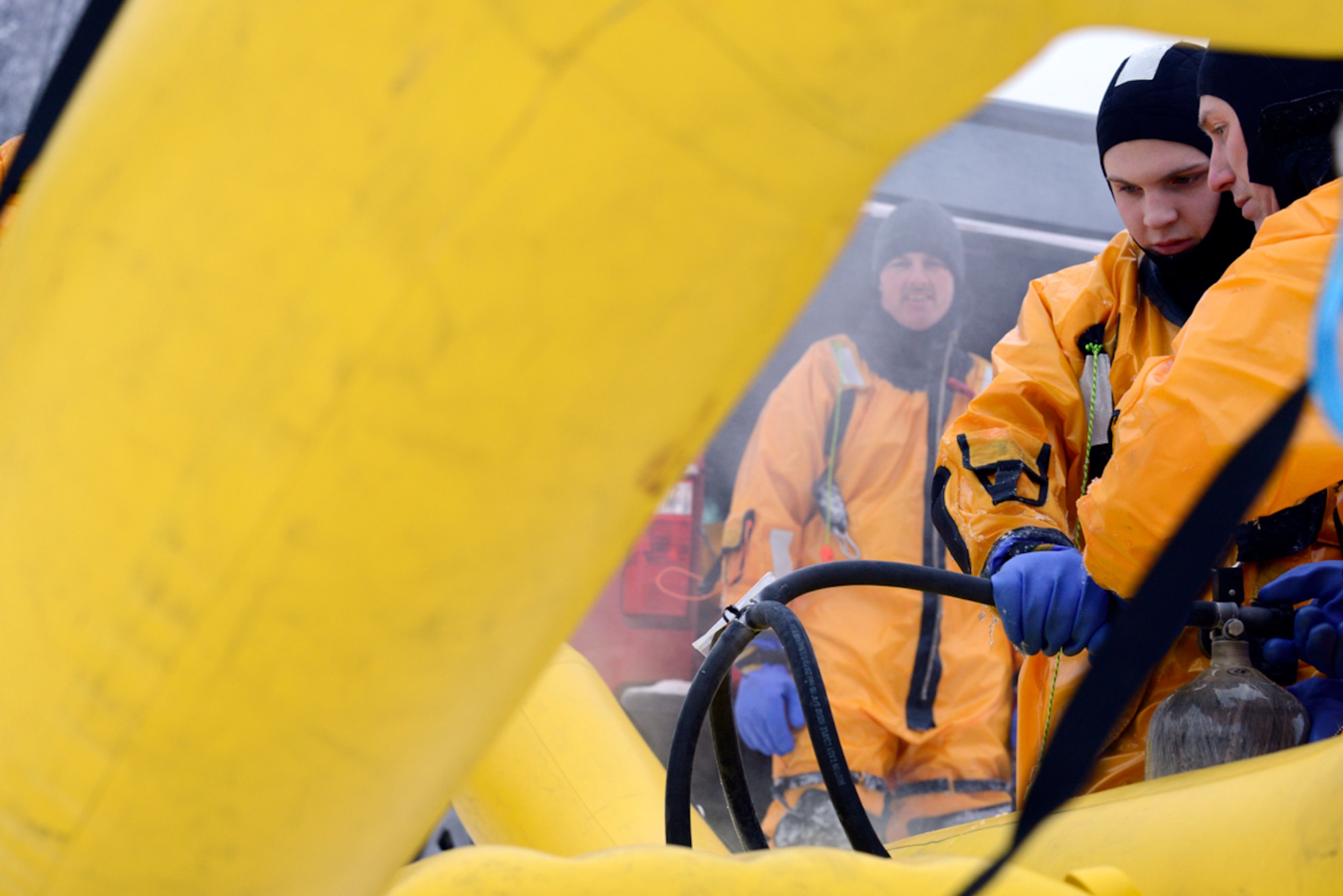 (Left right) Louis Larousse observes Airman 1st Class Matthew Brooks and Michael Campbell inflate a rapid-deployment craft inflatable rescue raft during ice water rescue training at Upper Sixmile Lake, Joint Base Elmendorf-Richardson, Alaska, Jan. 13, 2014.  The RDC allows firefighters to quickly reach a victim and safely retrieve them from the ice or water. Larouuse, Brooks and Campbell are assigned to the 673d Civil Engineer Squadron firefighters. (U.S. Air Force photo/Staff Sgt. Sheila deVera)
