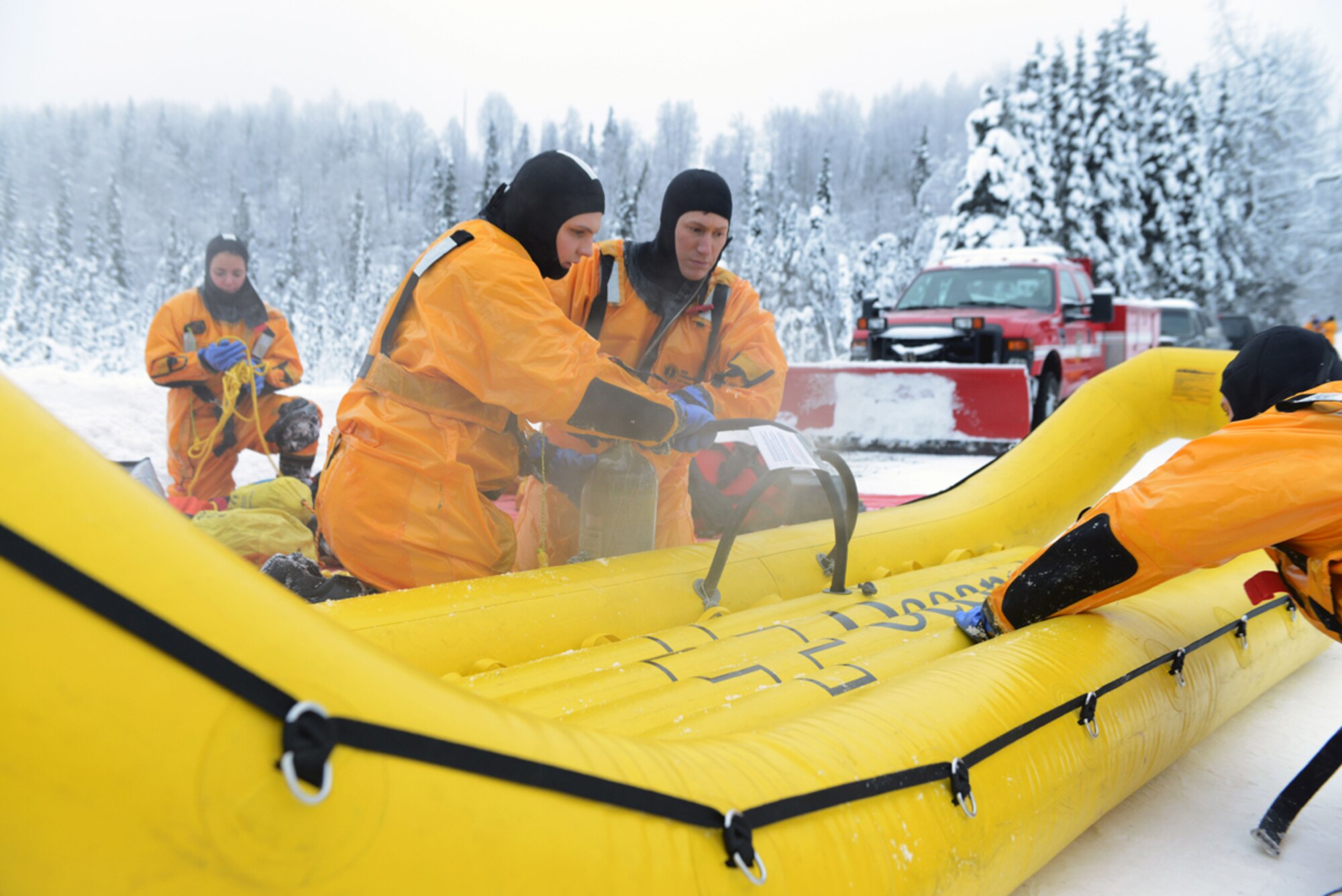 JOINT BASE ELMENDORF-RICHARDSON, Alaska -- Airman 1st Class Matthew Brooks, Staff Sgt. Cory Ford and Michael Campbell, firefighters with the 673d Civil Engineer Squadron, inflate a banana boat used for ice water rescue training at Upper Otter Lake on Joint Base Elmendorf-Richardson Jan. 11. The firefighters train their staff annually to stay proficient in ice water rescue since Alaska lakes are frozen nine to 10 months of the year. (U.S. Air Force photo/Airman 1st Class Ty-Rico Lea)