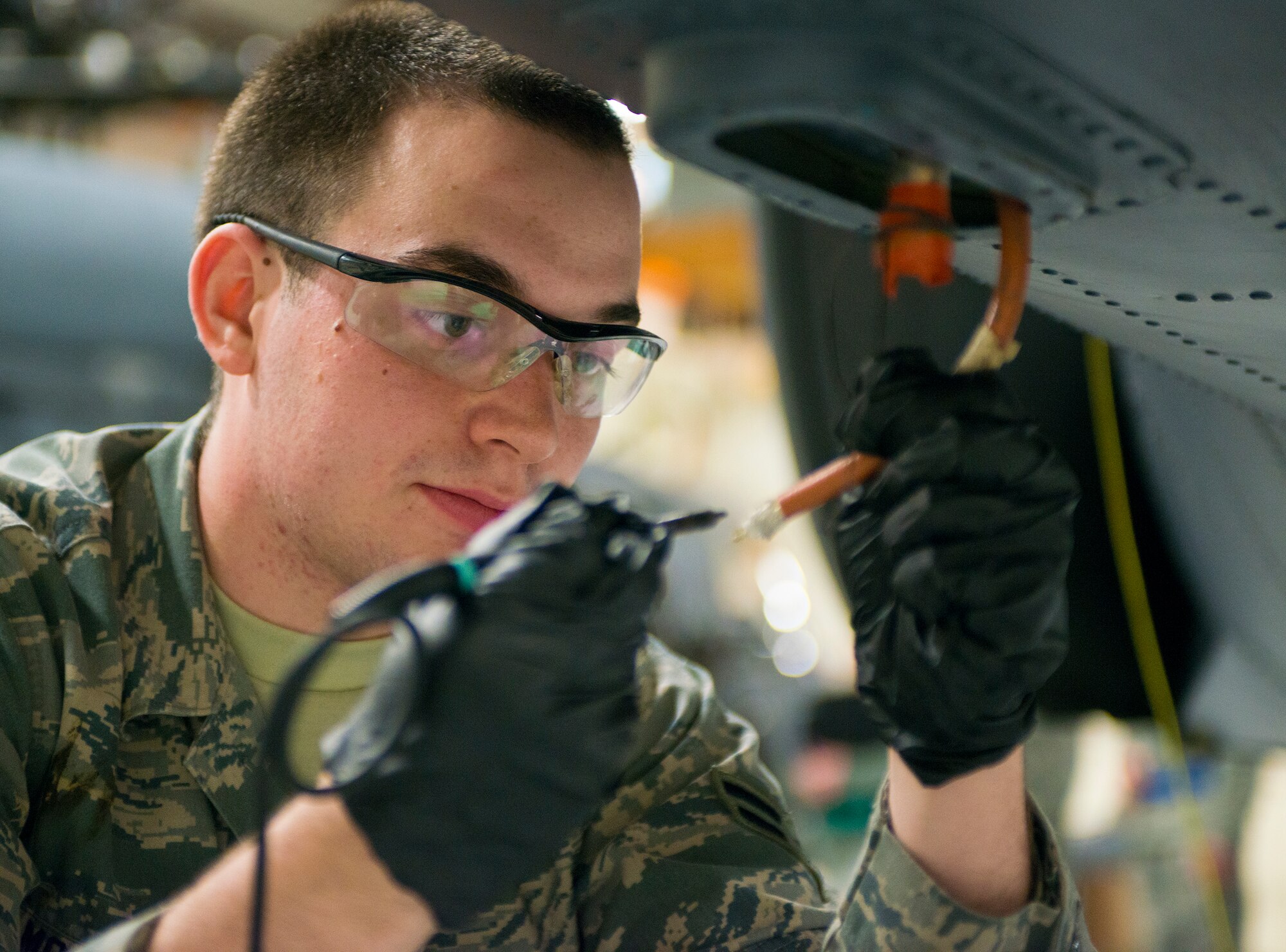U.S. Air Force Airman 1st Class Kevin McGraw, 723d Aircraft Maintenance Squadron crew chief, prepares a radio frequency transmission cable for soldering at Moody Air Force Base, Ga., Jan. 14, 2014. McGraw and a team of Airmen prepared an HH-60G Pave Hawk for inspection as part of a wing-wide exercise. (U.S. Air Force photo by Airman 1st Class Ryan Callaghan/Released)
