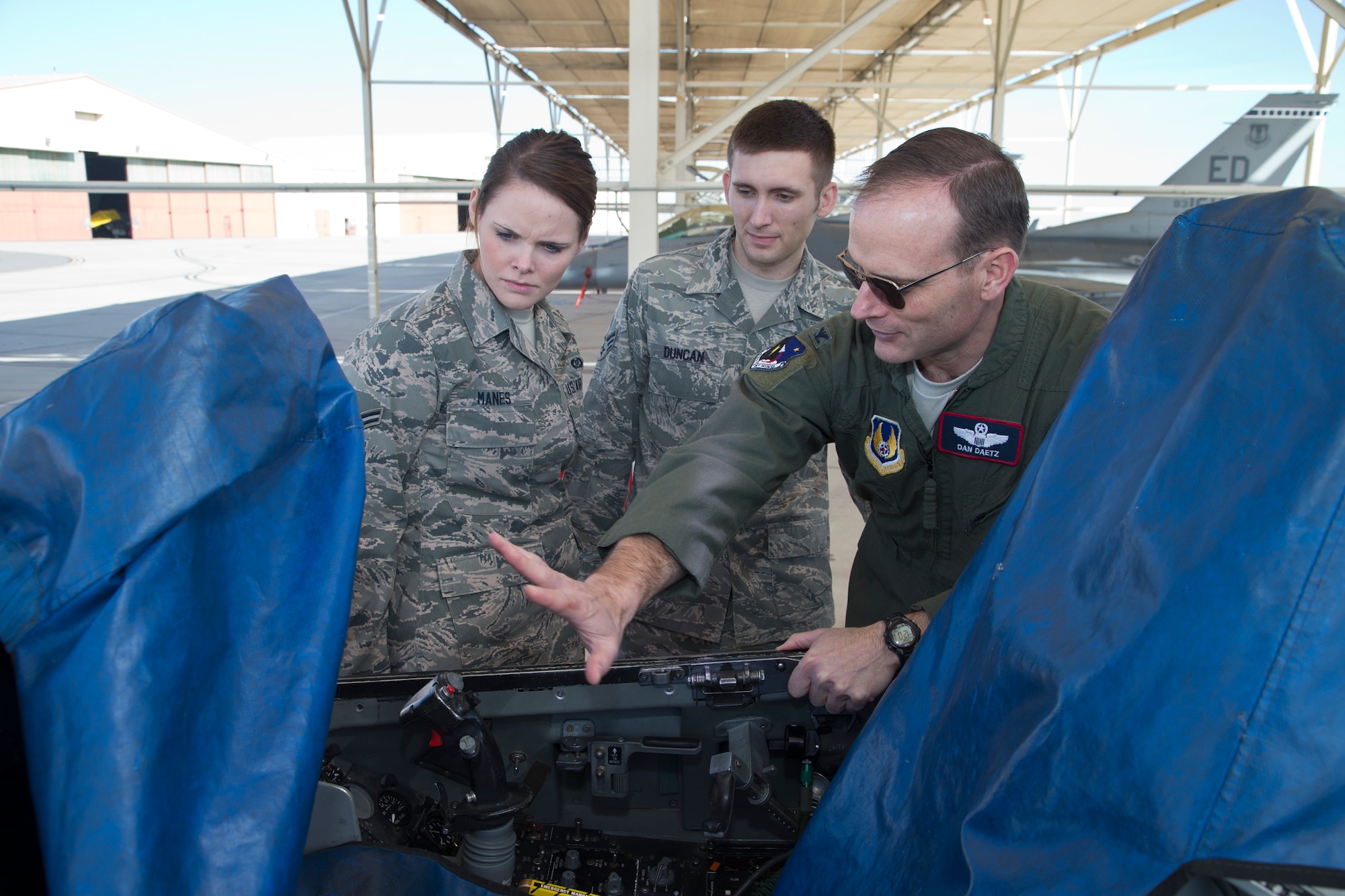 Col. Dan Daetz, 412th Test Wing vice commander, gives Airman 1st Class Breanna Manes and Senior Airman John Duncan a close-up tour of an F-16 cockpit as part of a newcomer and familiarization tour for Command Post personnel on Jan. 8. Command Post specialists experienced a "windshield tour" so they could see unique elements of Edwards' mission, such as Ridley Mission Control Center, the Rogers Dry Lakebed and the basic layout of the flightline. (U.S. Air Force photo by Bobbi Zapka)