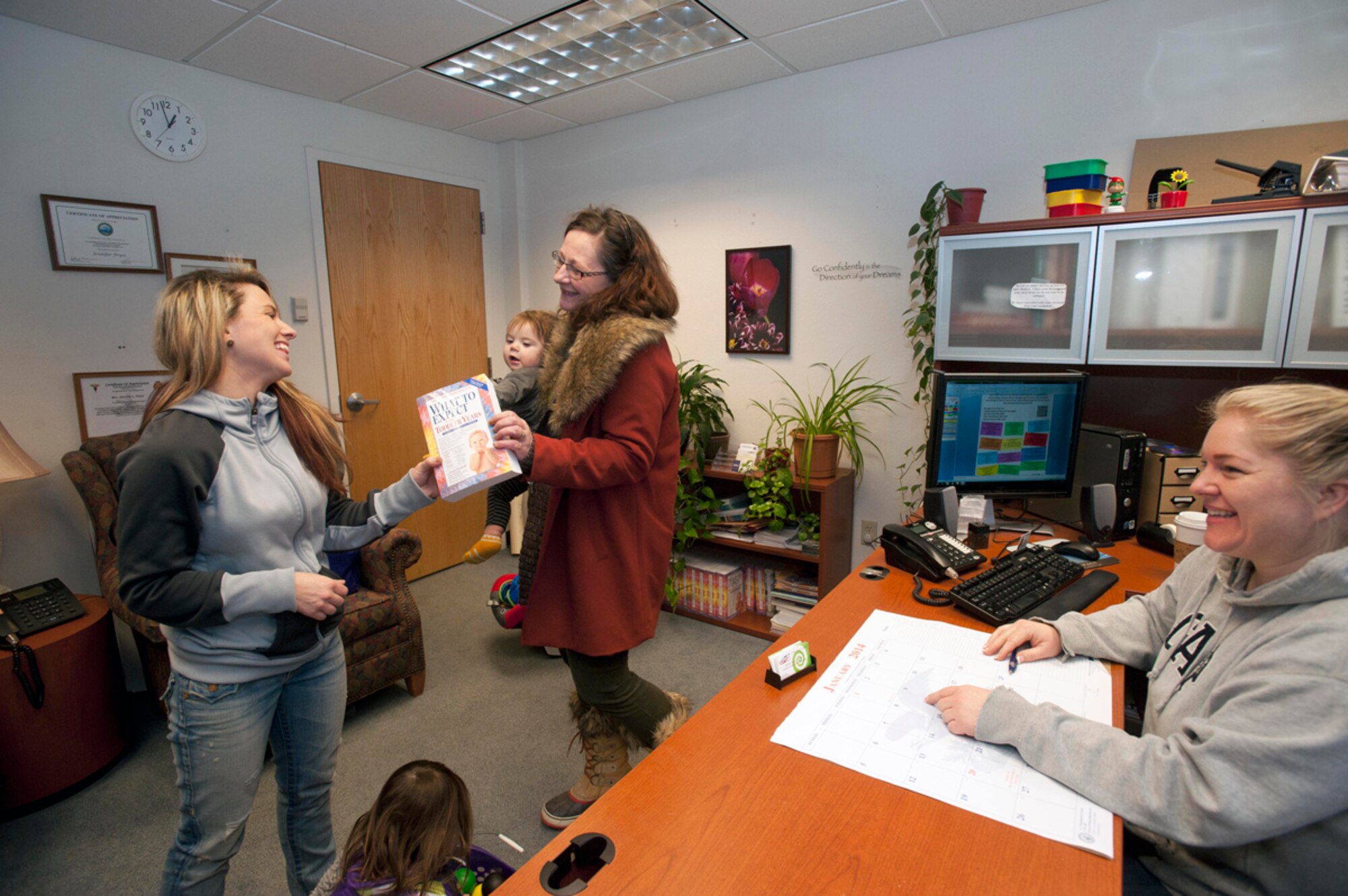 Petra Cooke, center, and Jennifer Frysz, right, give Samantha Diaz, left, a free parenting book from the Family Advocacy Outreach office at Joint Base Elmendorf-Richardson, Jan. 13. Cooke, wife of Army Master Sgt. Travis Cooke, acting first sergeant for Comanche Company, 1st Battalion (Airborne), 501st Infantry Regiment, 4th Infantry Brigade Combat Team (Airborne), 25th Infantry Division, met Diaz, a new Air Force wife, only a few hours prior, and chose to help her with her children, obtaining an identification card, signing up in TRICARE, and more, more her husband is in Basic Military Training at Joint Base San Antonio, Texas. (U.S. Air Force photo/Staff Sgt. Robert Barnett)