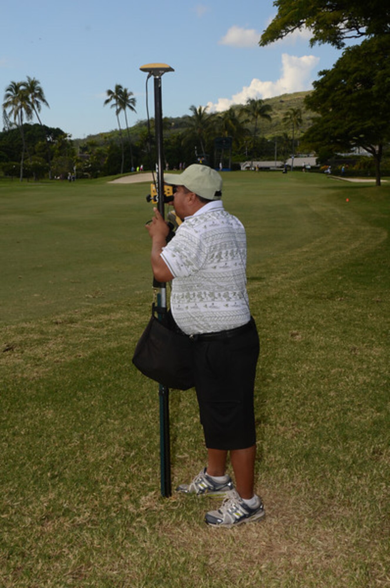 Tech. Sgt. Ed Dumlao, a water fuels systems maintenance journeyman with the 624th Civil Engineering Squadron, operates a survey-grade laser on the 14th fairway at the Sony Open PGA Tour golf tournament, Waialae Country Club, Honolulu, Hawaii, Jan. 12, 2014. The laser is used to record everything from the location of each ball, the position in which it comes to rest, the distance it travels and the time it is struck. (Courtesy photo by Tobias Manuputy/Released)
