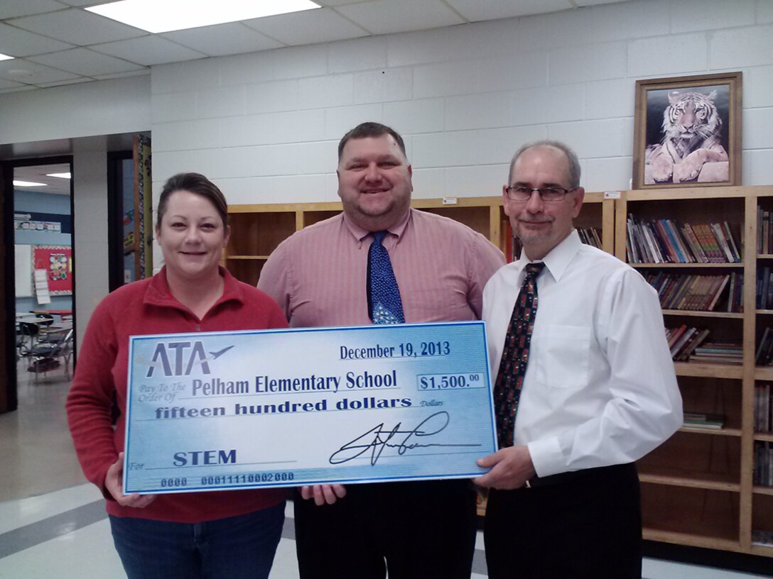 Pelham Elementary School received a $1500 STEM donation from ATA toward the purchase of a Promethean Board. The board features interactive lesson instruction that features manipulatives, modeling and math vocabulary online. Pelham Elementary School teacher Amy Houk (left) and Principal Willie Childers (center) are shown here receiving the donation from Tony Medley, from the ATA Flight System Plant Assets Branch Engineering and Planning. (Photo provided)