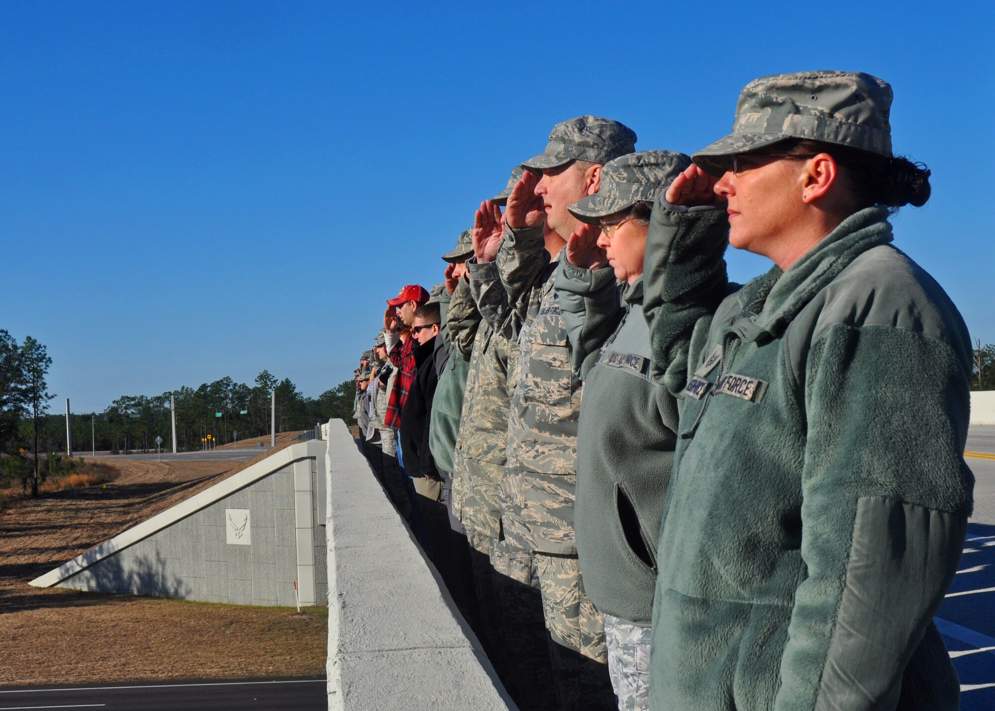 Duke Field reservists salute the hearse carrying Army Sgt. 1st Class William Lacey from atop the overpass between Duke and the Army's 7th Special Forces Group (Airborne) cantonment Jan. 15.   More than 40 Airmen and Soldiers lined the overpass to render honors to the local area native Soldier who was killed in action in Afghanistan.  (U.S. Air Force photo/Dan Neely)