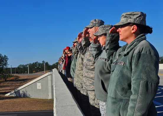 Duke Field reservists salute the hearse carrying Army Sgt. 1st Class William Lacey from atop the overpass between Duke and the Army's 7th Special Forces Group (Airborne) cantonment Jan. 15.   More than 40 Airmen and Soldiers lined the overpass to render honors to the local area native Soldier who was killed in action in Afghanistan.  (U.S. Air Force photo/Dan Neely)