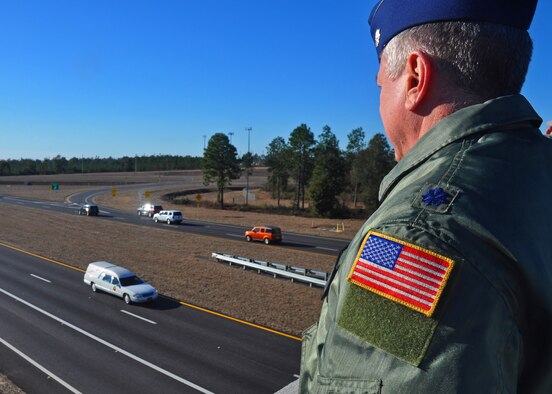 A Duke Field reservist salutes the hearse carrying Army Sgt. 1st Class William Lacey from atop the overpass between Duke and the Army's 7th Special Forces Group (Airborne) cantonment Jan. 15.   More than 40 Airmen and Soldiers lined the overpass to render honors to the local area native Soldier who was killed in action in Afghanistan.  (U.S. Air Force photo/Dan Neely)