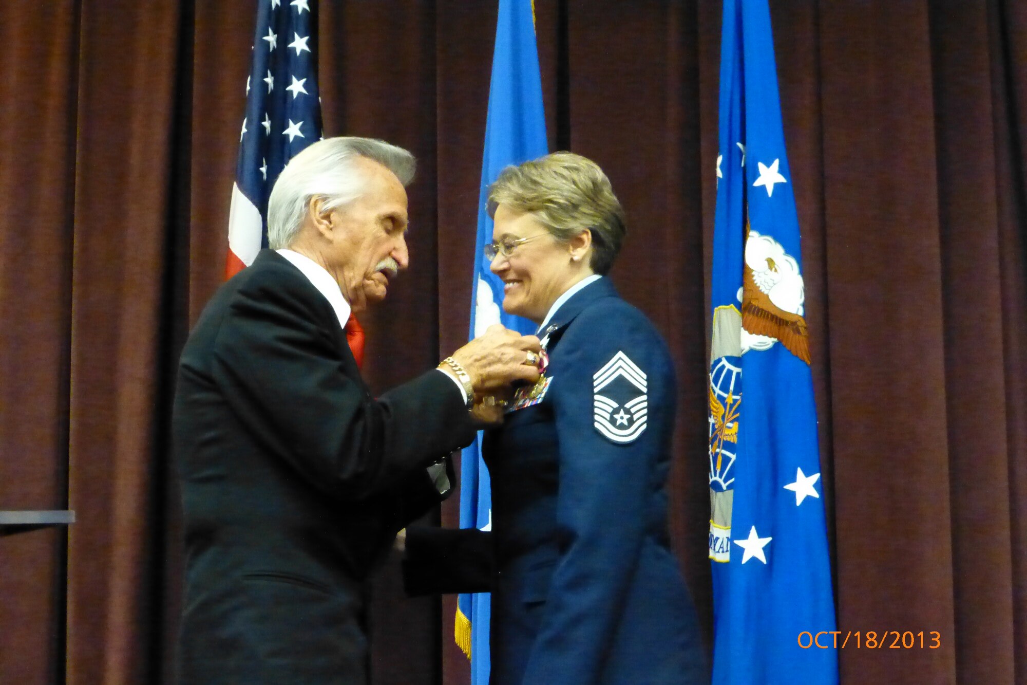 Chief Master Sgt. Kathy Cooper, Band of Mid-America flutist, receives her retirement pin from the doctor who encouraged her to join the Air Force 27 years ago, despite other doctors telling her she could not handle it because of depression and suicidal thoughts. Cooper now plans on finishing her Master of Arts in Biblical Theology and becoming a missionary. (Courtesy photo)
