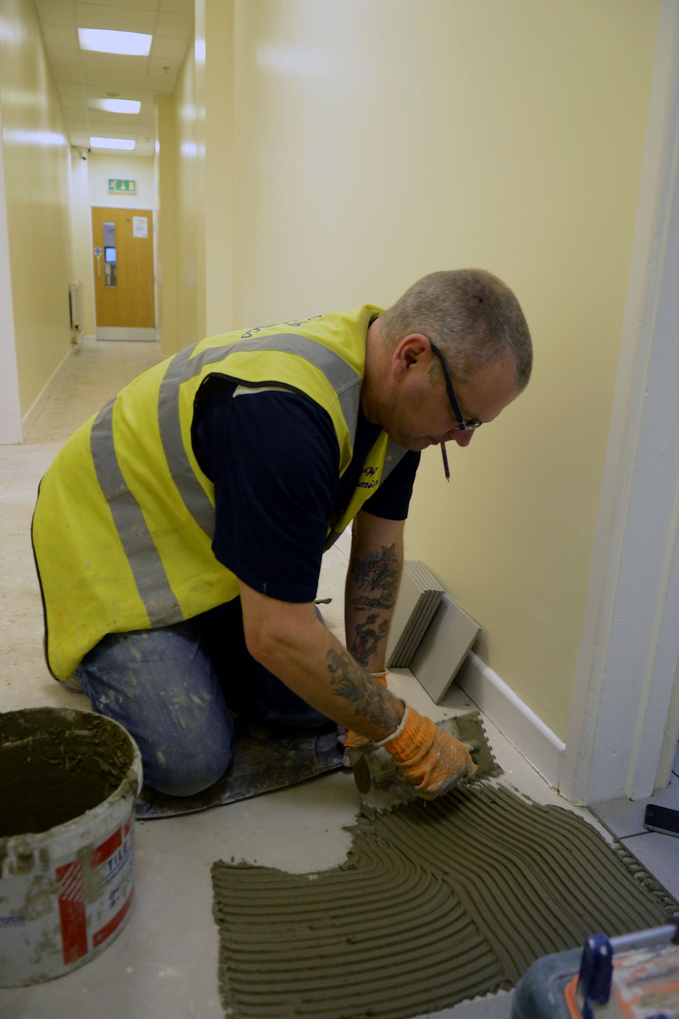 A contractor lays down tile Nov. 4, 2013, at the Northside Fitness Center on RAF Mildenhall, England. The fitness center has been closed since October 2013 for renovations. (U.S. Air Force photo by Airman 1st Class Kyla Gifford/Released) 