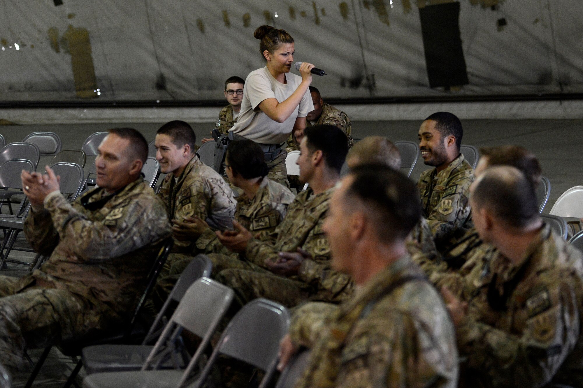 U.S. Air Force Staff. Sgt. Kelly Perry, Air Force Central Command Band vocalist, entertains a crowd of Airmen in a maintenance hangar at the 455th Expeditionary Maintenance Group, Bagram Air Field, Afghanistan, Dec. 21, 2013. The AFCENT band performed at various locations around Bagram Air Field during their 15 day tour of Afghanistan. Perry a Crestwood, Ky., native, is deployed from the Air Force Band of Flight, Wright Patterson, Air Force Base, Ohio. (U.S. Air Force photo by Tech. Sgt. Jason Robertson/released)
