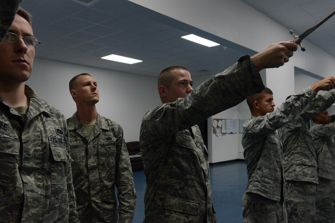 Tech. Sgt. Anthony Miller, Blue Knights Honor Guard lead trainer, inspects the angle an honor guard team member holds his sword at while the team practices forming a saber cordon Jan. 8, 2014, on Andersen Air Force Base, Guam. The honor guard mission is to maintain and employ a ceremonial capability to represent the Air Force at public and official ceremonies. (U.S. Air Force photo by Airman 1st Class Emily A. Bradley/Released)
