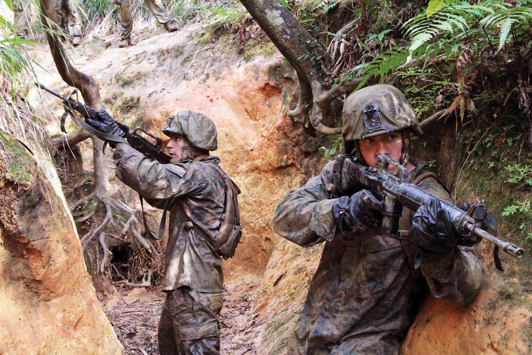 U.S. Marine Corps Lance Cpl. Remington Ostrem wades into water as Marine Corps Cpl. Ronald Mitchell follows closely behind at the beginning of an endurance course at the Jungle Warfare Training Center on Camp Gonsalves in Okinawa, Japan, Jan. 12, 2014. 