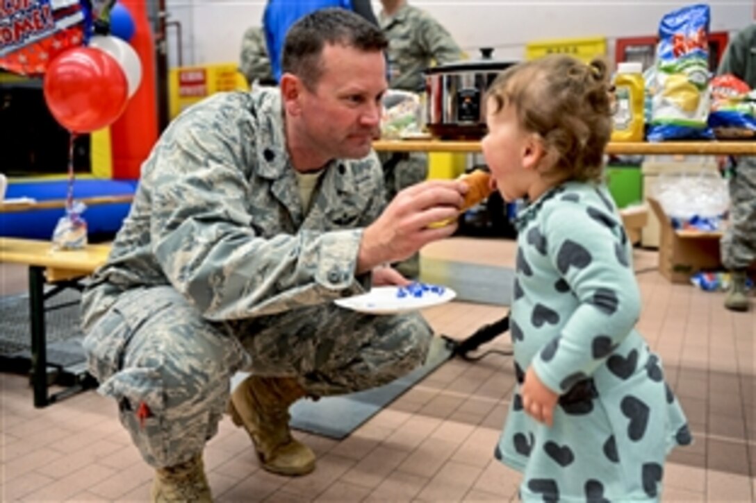 U.S. Air Force Lt. Col. Robert Long gives his daughter a hot dog on Spangdahlem Air Base, Germany, Jan. 15, 2014. The airmen returned from a deployment to Southwest Asia to support Operation Enduring Freedom. Long commands the 606th Air Control Squadron. 