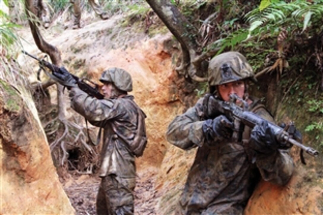 U.S. Marine Corps Lance Cpl. Remington Ostrem wades into water as Marine Corps Cpl. Ronald Mitchell follows closely behind at the beginning of an endurance course at the Jungle Warfare Training Center on Camp Gonsalves in Okinawa, Japan, Jan. 12, 2014. 