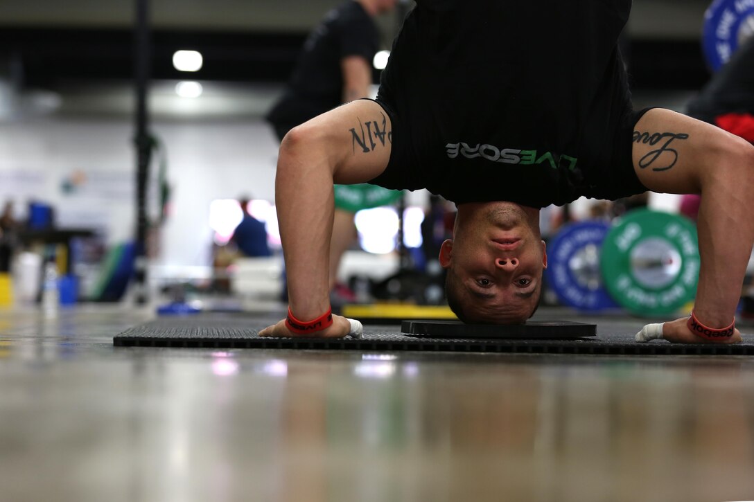 Sgt. Aaron Gardner, a training clerk with Headquarters and Headquarters Squadron, Marine Corps Air Station Miramar, Calif., performs a handstand push up while warming up during the Orange County Throwdown at the Orange County Fair Grounds, Jan. 11. Gardner pushed himself through each grueling repetition and, despite an injury to one of his abdominal muscles early the second day, finished 20th.