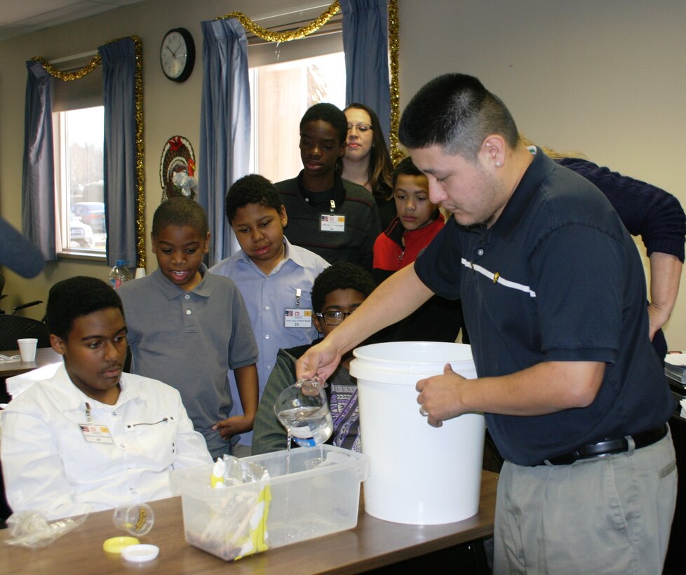 ALBUQUERQUE, N.M., -- Architect Lionel Romero pours water on a model dam to test its design Jan. 3, 2014. Students gathered at the District's main office to learn more about STEM and the Corps of Engineers.