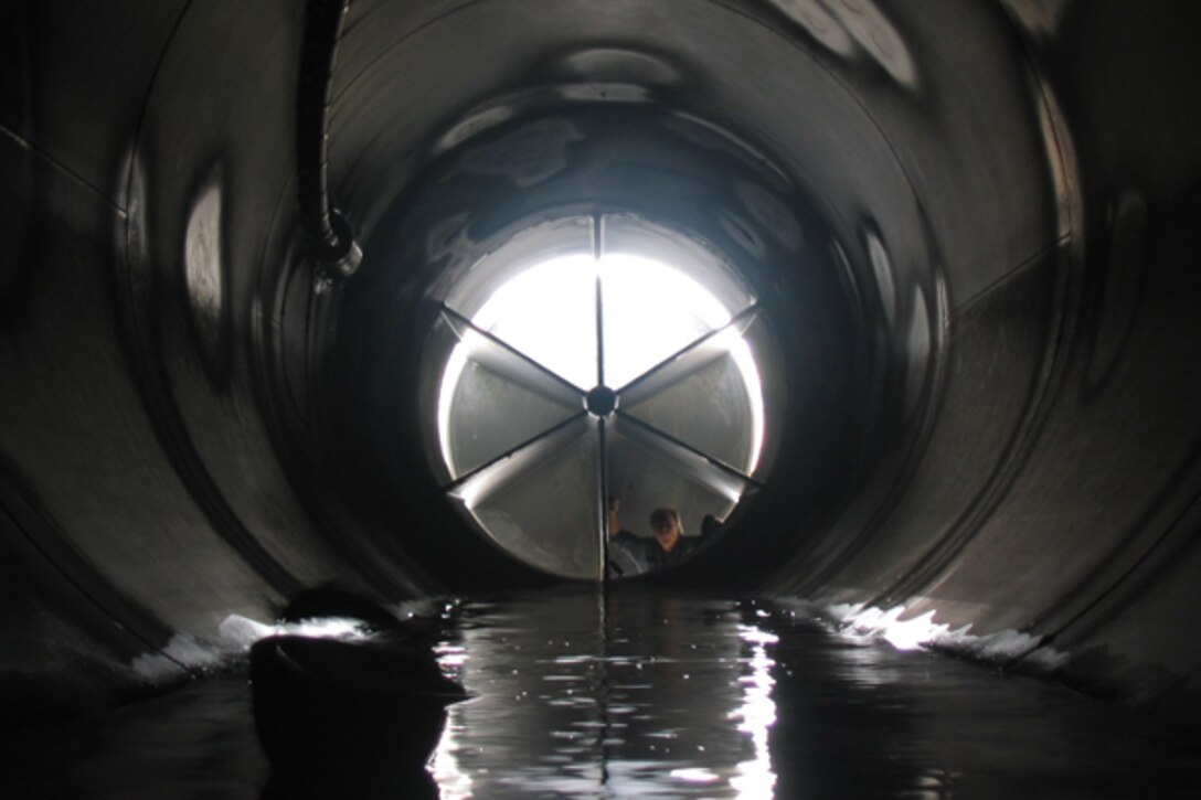 A worker peers into the Lucky Peak Dam Auxilliary Tunnel through an open cone valve.
