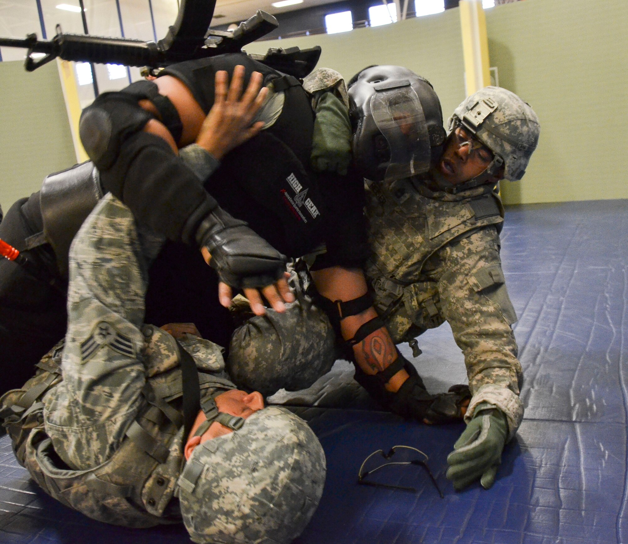 Senior Airman Savas Rivera, 612th Support Squadron, along with Capt. Carlos Semidey,  1st Battlefield Coordination Detachment, wrestle with a non compliant combative during the Modern Army Combatives Program (MACP) Basic Combatives Course Level 1 at Davis-Monthan Air Force Base, Ariz., Jan. 16, 2014. The 40-hour course focuses on the three phases of basic fighting strategy; close the distance, gain the dominate position, and how to finish the fight. (U.S. Air Force photo by Staff Sgt. Adam Grant/Released)