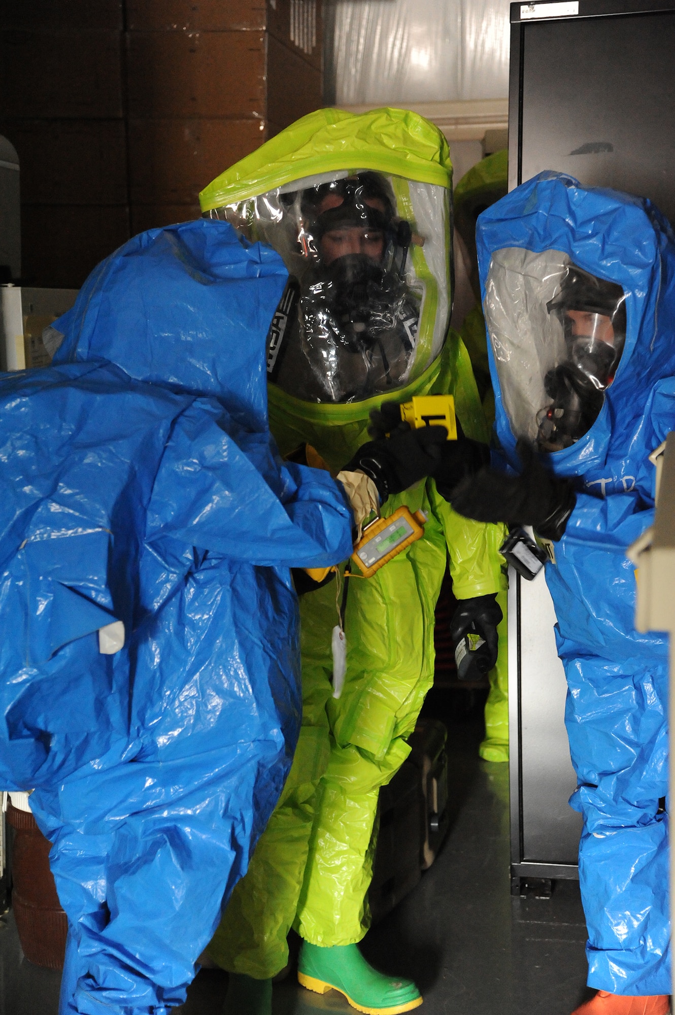 Senior Airman Der Her, left, hands Airman 1st Class Brittany Barat, right, evidence markers to put near a simulated chemical lab as Airman 1st Class Joel Rogel assists during an exercise at the Montana Air National Guard in Great Falls, Mont., on Jan. 13. All three Airmen are part of Malmstrom’s Chemcial, Biological, Radiological and Nuclear Emergency Response Force Team. (U.S. Air Force photo/Senior Airman Cortney Paxton)