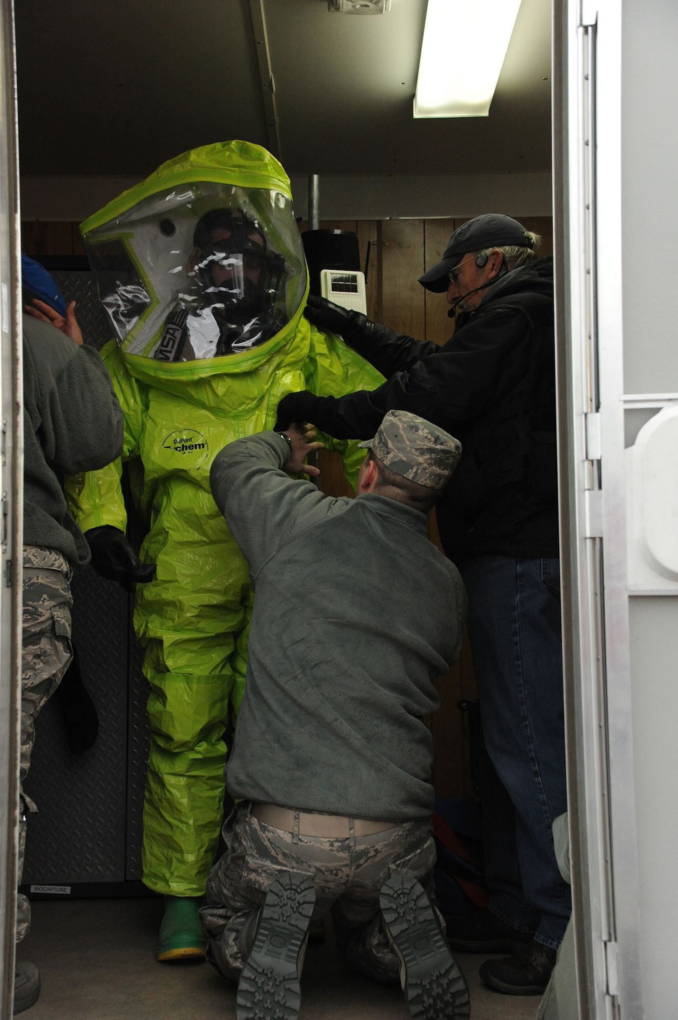 Royce Shipley, 341st Civil Engineer Squadron senior emergency manager (right), and Airman 1st Class Sean McLarnon, 341st Medical Operations Squadron bioenvironmental engineer technician (center), help Airman 1st Class Joel Rogel, 341st MDOS bioenvironmental engineer technician, don his Level-A chemical protective equipment during a joint exercise at the 120th Fighter Wing on Jan. 13. The joint exercise allowed various organizations to work together building confidence and coordinating processes so all entities are prepared to work as a team.  (U.S. Air Force photo/Senior Airman Cortney Paxton)