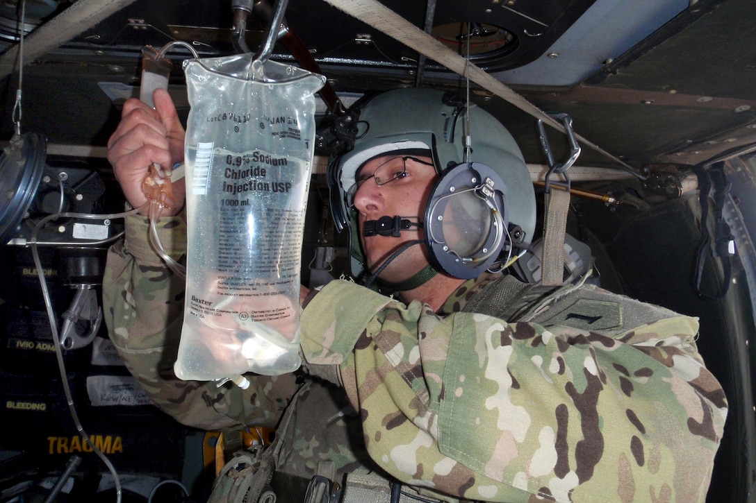 U.S. Army Spc. Israel Figueroa prepares an IV bag for use during a medical evacuation mission to transport a critically injured Afghan soldier in Zabul province, Afghanistan, Jan. 2, 2014. Figueroa is a flight medic assigned to Company C, 2nd General Support Aviation Battalion, 1st Aviation Regiment.