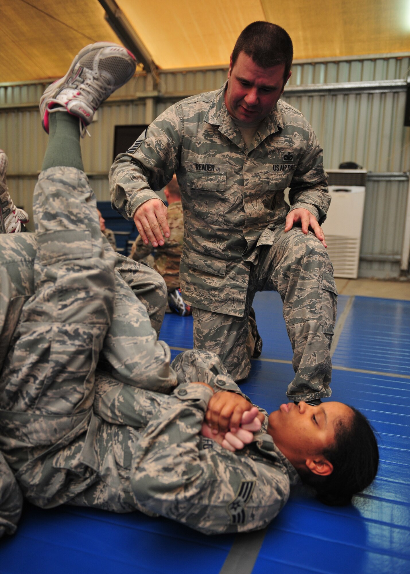 Air Force Master Sgt. Robert Reader, 380th Air Expeditionary Wing Check Six, instructs Air Force Senior Airman Cherelle Doss, 380th Expeditionary Force Support Squadron services journeyman, how to properly perform an arm bar during an Air Force combatives class at an undisclosed location in Southwest Asia, Jan. 10, 2014. (U.S. Air Force photo by Staff Sgt. Michael Means/Released)