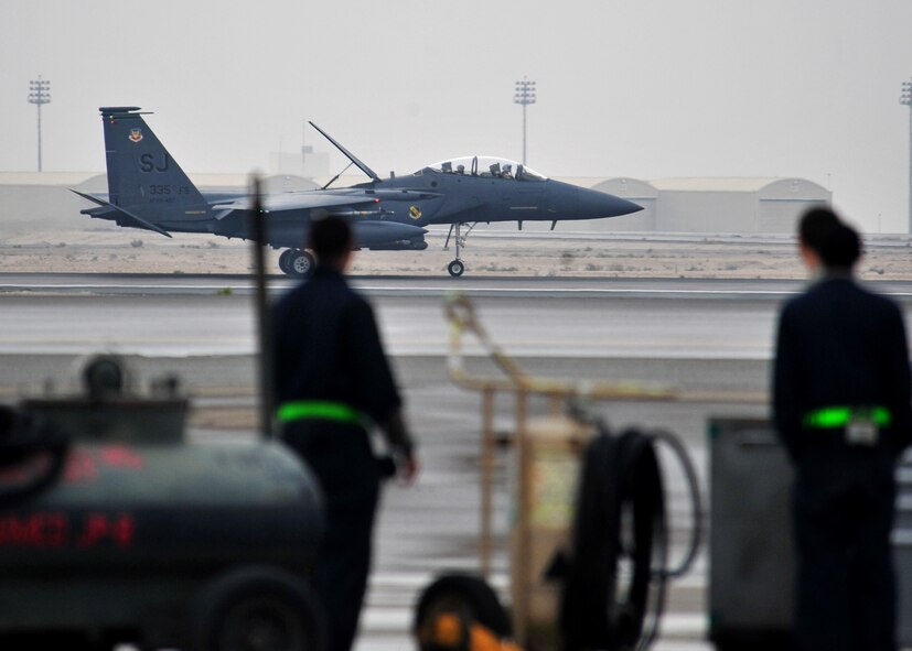 Members of the 380th Expeditionary Maintenance Group watch as the F-15E fighter aircraft flag ship flying Air Force Maj "Dozer," a weapon systems officer assigned to the 335th Expeditionary Fighter Squadron, lands at an undisclosed location in Southwest Asia, Jan. 12, 2014. Dozer just completed his 1,000th combat flying hour. (U.S. Air Force photo by Staff Sgt. Michael Means/Released)