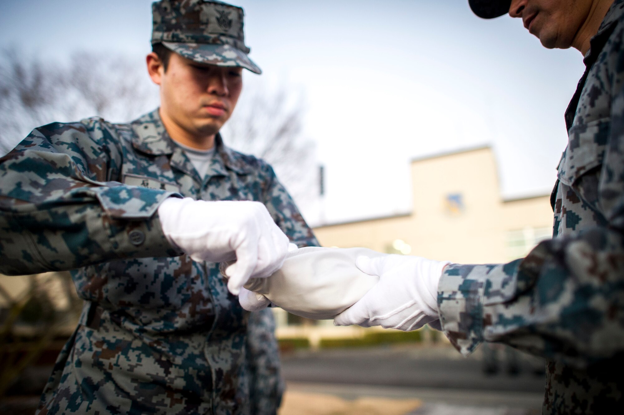 Members from the Japanese Air Self-Defense Force fold the Japanese flag during a retreat ceremony Jan. 17, 2014 at Yokota Air Base, Japan. This retreat is the first ever bilateral wing retreat with 12 Air Force members and 12 Japanese Air Self-Defense Force members in formation. (U.S. Air Force Photo by Staff Sgt Stacy Moless) 