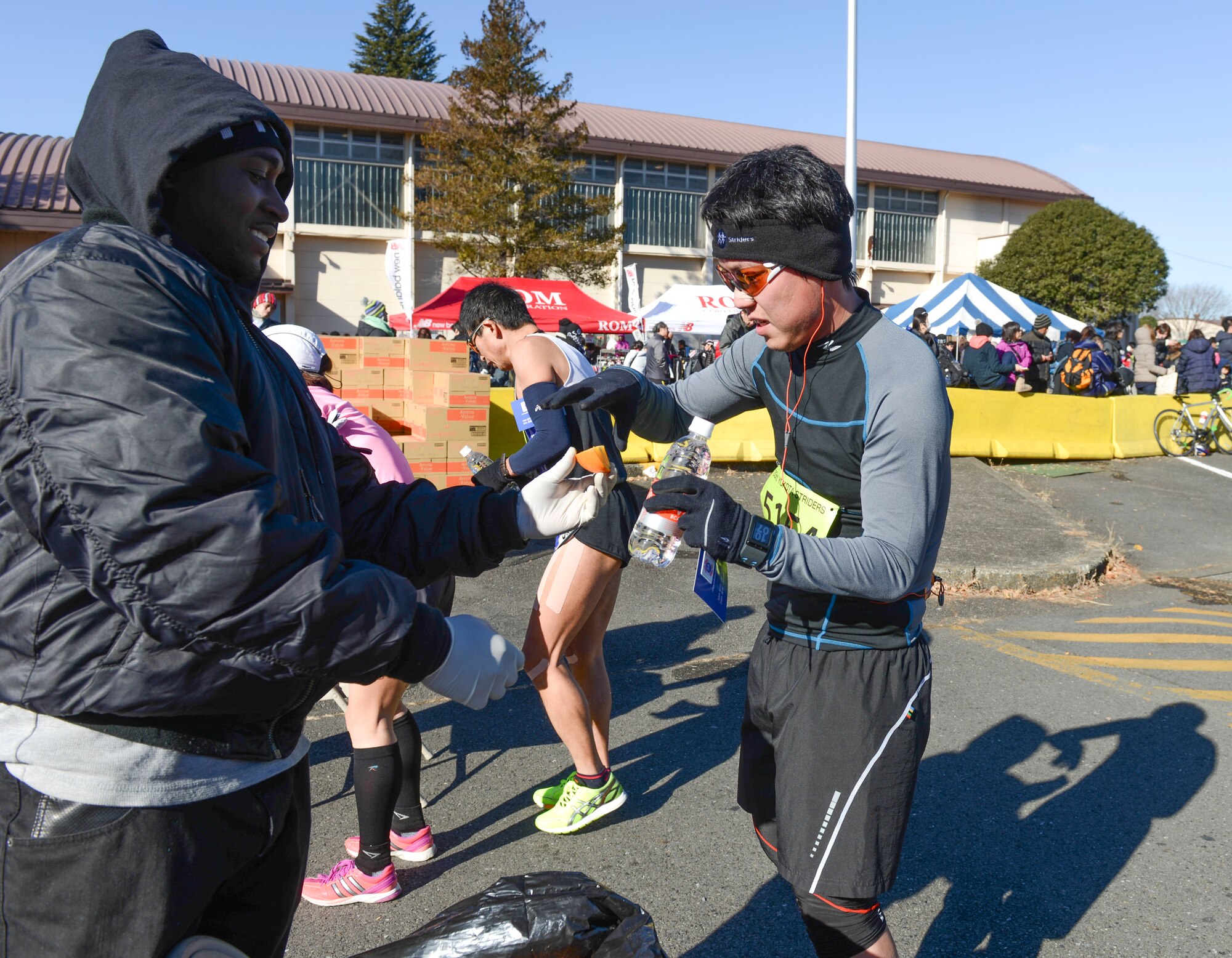 Staff Sgt. Troy Sheppard, 374th Security Forces Squadron military working dog trainer, hands fruit to a runner who just completed one of the annual Frostbite Run races at Yokota Air Base, Japan, Jan.19, 2014.  There were oranges, bananas and drinks available for the runners after the race as well as booths with other types of food. (U.S. Air Force photo by Airman 1st Class Meagan Schutter/Released)