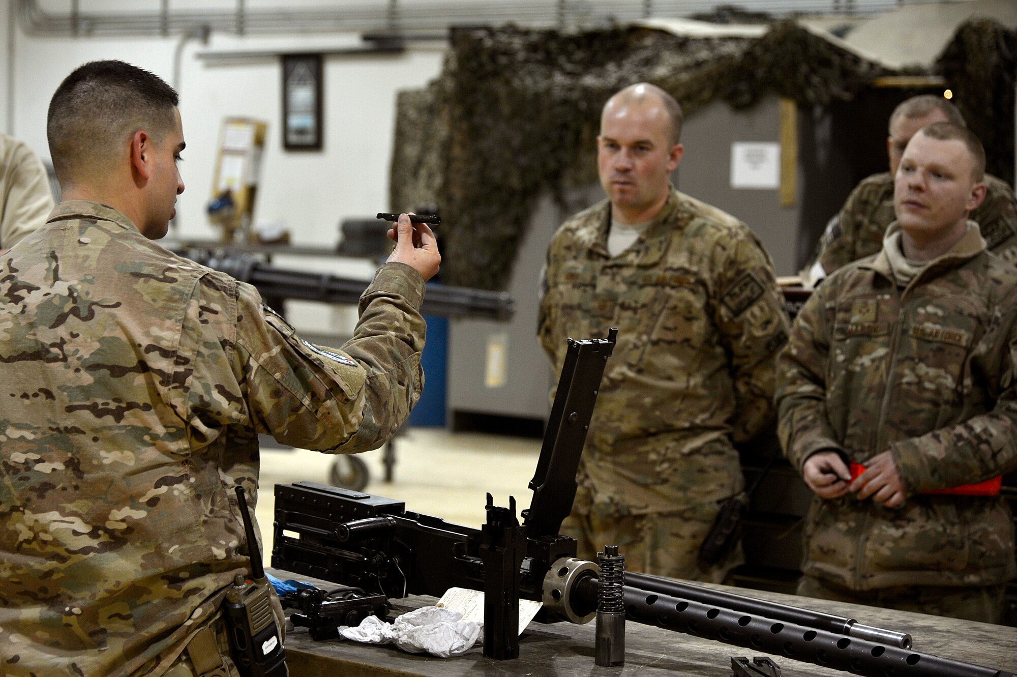 U.S. Air Force Tech. Sgt. Vincent Lopez, 83rd Expeditionary Rescue Squadron weapons lead expeditor, explains a piece of the GAU 18 machine gun to Airmen assigned to the 455th Expeditionary Maintenance Squadron armament shop at Bagram Airfield, Afghanistan, Jan. 19, 2014. Lopez led a training session to familiarize the Airmen with the weapons on HH-60G Pave Hawks. Lopez is deployed from the 718th Aircraft Maintenance Squadron at Kadena Air Base, Japan, and is a native of El Paso, Texas. (U.S. Air Force photo by Senior Airman Kayla Newman/Released)