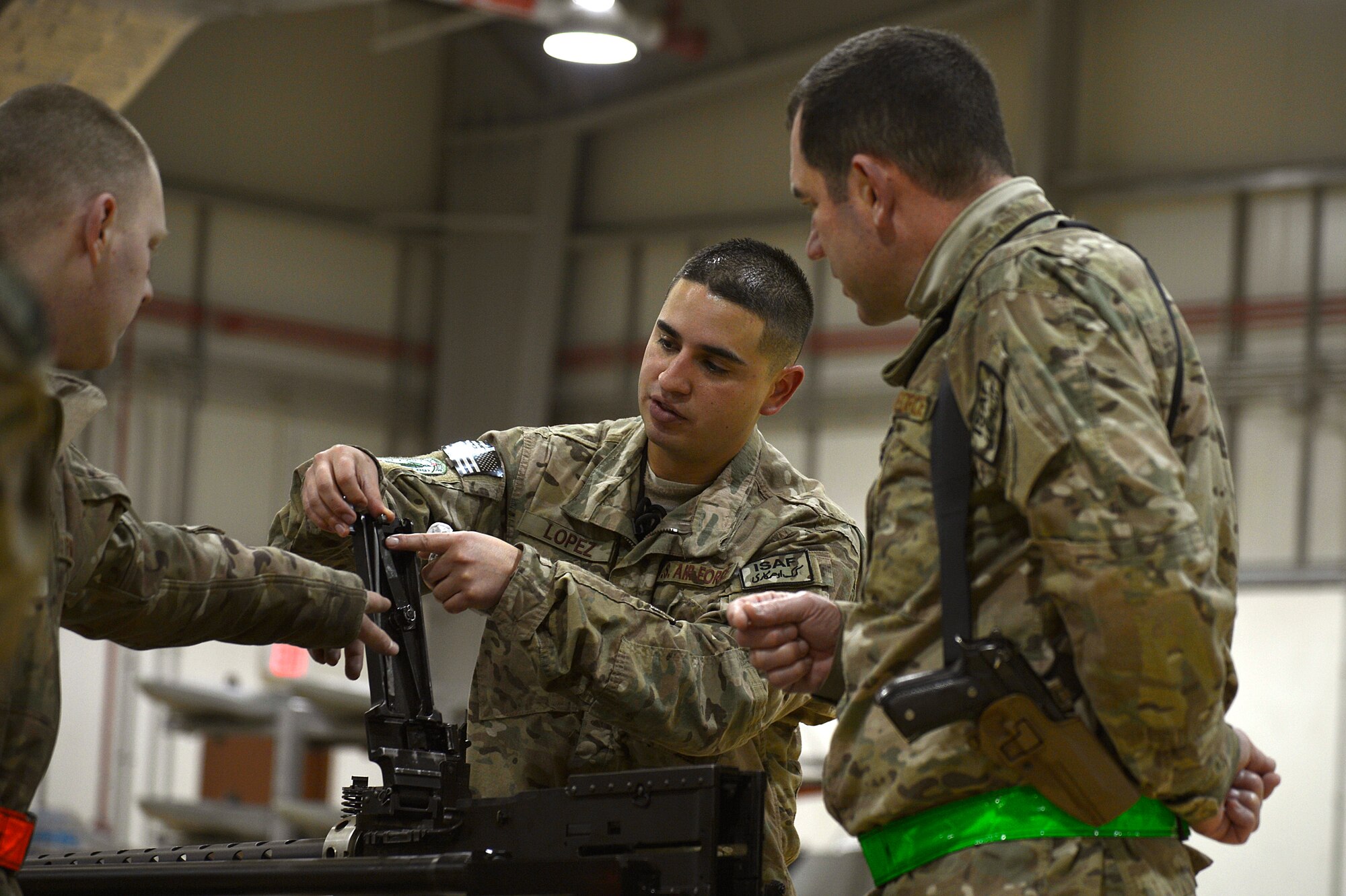 U.S. Air Force Tech. Sgt. Vincent Lopez, 83rd Expeditionary Rescue Squadron weapons expeditor, explains a piece of the GAU 18 machine gun to Airmen assigned to the 455th Expeditionary Maintenance Squadron armament shop at Bagram Airfield, Afghanistan, Jan. 19, 2014. Lopez led a training session to familiarize the Airmen with the weapons on HH-60G Pave Hawks. Lopez is deployed from the 718th Aircraft Maintenance Squadron at Kadena Air Base, Japan, and is a native of El Paso, Texas. (U.S. Air Force photo by Senior Airman Kayla Newman/Released)