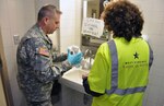 National Guard Soldier assisting at Charleston, W. Va., water emergency takes a sample from a tap to check for safety.