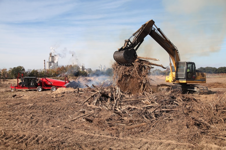 A worker piles debris from Dredge Material Containment Area 1N into a pit of fire. The 130-acre dredge disposal area, located on Onslow Island in Georgia, is being reactivated by the U.S. Army Corps of Engineers, Savannah District through a process called air curtain burning. 