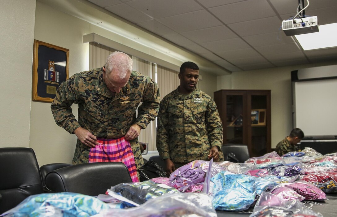 Lieutenant Cmdr. David Dinkins, left, chaplain, and Chief Petty Officer Emmanuel Essenete, medical chief, both with the 15th Marine Expeditionary Unit, look through pajamas for their children during a pajama giveaway at the unit’s command post aboard Camp Pendleton, Calif., Jan. 16, 2014. The pajamas were donated by Davis Magnet School in Costa Mesa, Calif. (U.S. Marine Corps photo by Cpl. Emmanuel Ramos/Released)