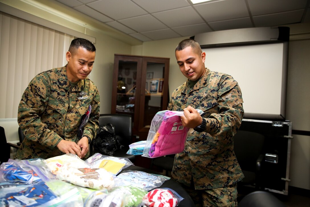 Petty Officer 1st Class Wendell Tabios, left, hospital corpsman, and Sgt. Sigilfredo Garcia, small-arms technician, both with the 15th Marine Expeditionary Unit, look through pajamas for their children during a pajama giveaway at the unit’s command post aboard Camp Pendleton, Calif., Jan. 16, 2014. The pajamas were donated by Davis Magnet School in Costa Mesa, Calif. (U.S. Marine Corps photo by Cpl. Emmanuel Ramos/Released)