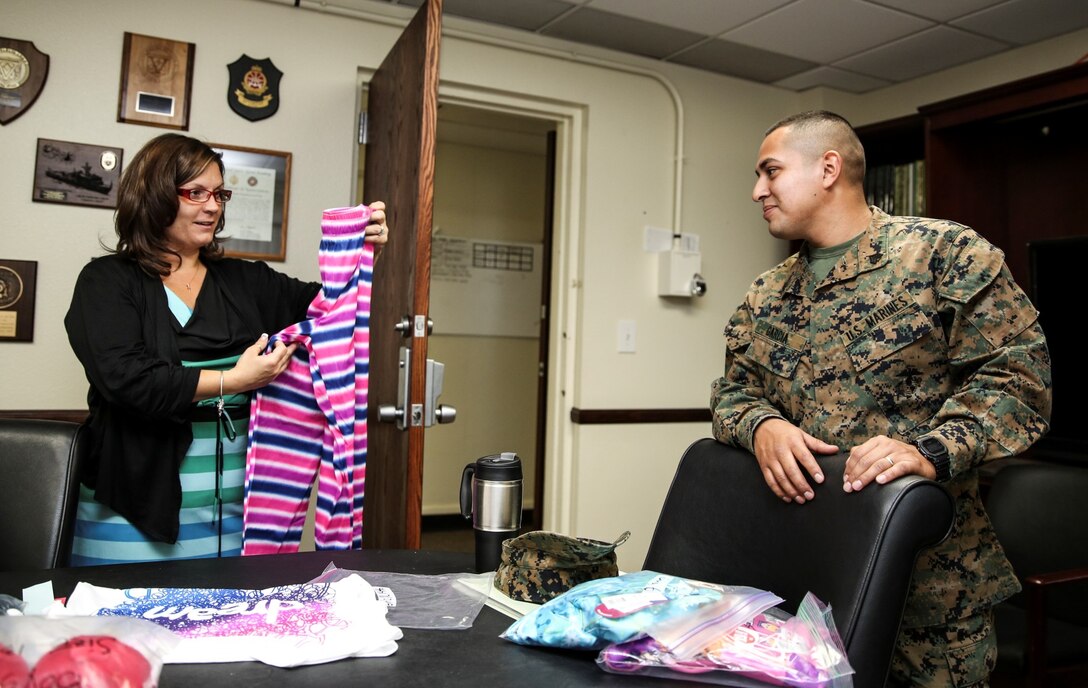 Nori Jackson, family readiness officer, shows Sgt. Sigilfredo Garcia, small arms technician, both with the 15th Marine Expeditionary Unit, a pair of pajamas during a pajama giveaway at the unit’s command post aboard Camp Pendleton, Calif., Jan. 16, 2014. The pajamas were donated by Davis Magnet School in Costa Mesa, Calif. (U.S. Marine Corps photo by Cpl. Emmanuel Ramos/Released)