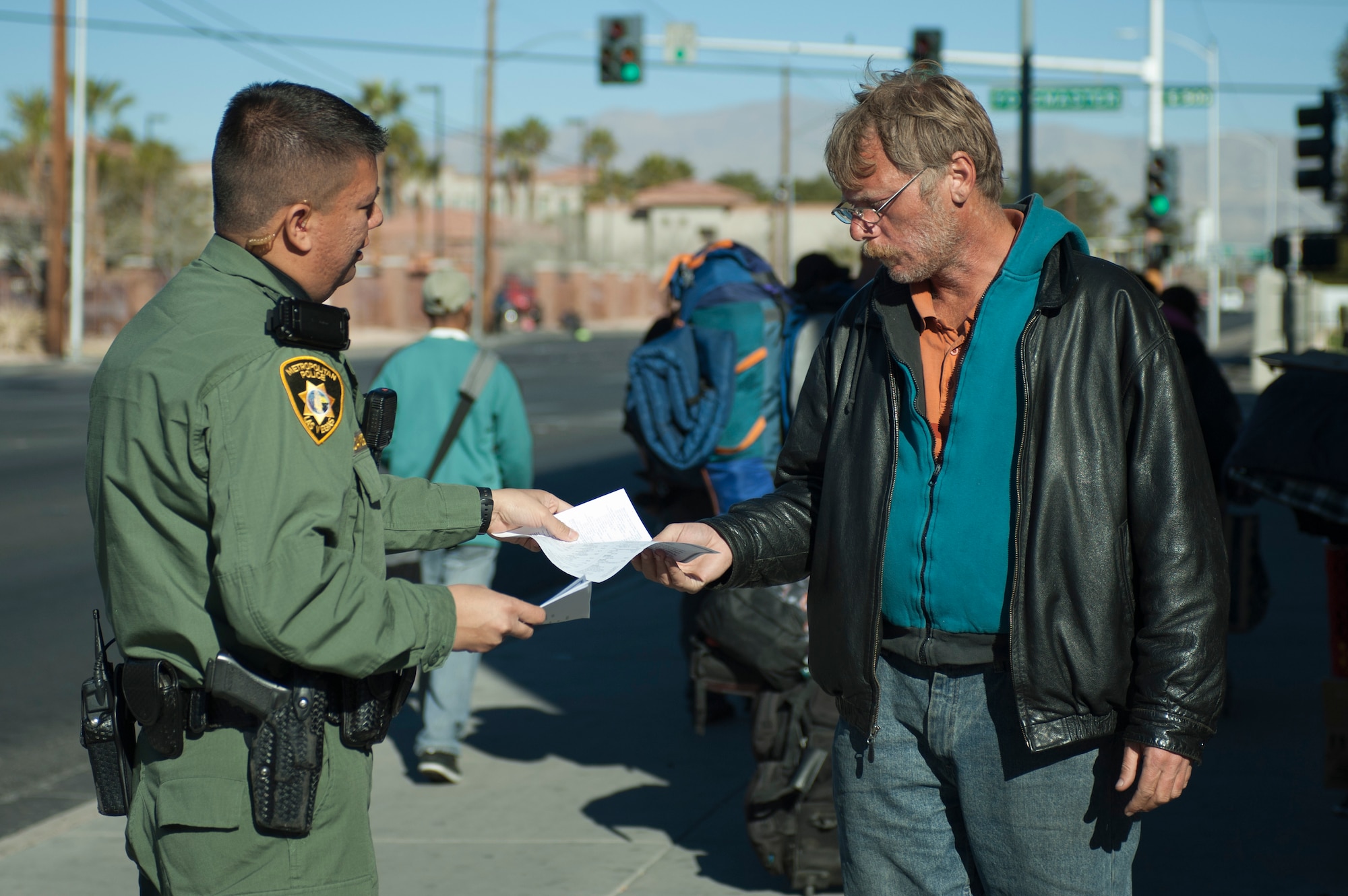 Aden Ocampogomez, Las Vegas Metropolitan Police Department police officer, hands out program information to the homeless during a routine patrol downtown Jan. 14, 2014, in Las Vegas. Programs provided to homeless people are designed to give them all the assistance they need to get them off the streets. (U.S. Air Force photo by Airman 1st Class Timothy Young)