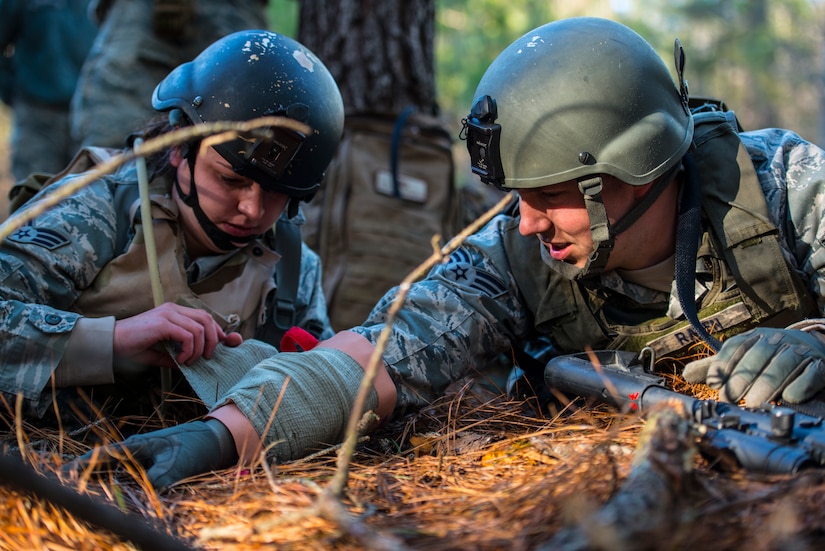 Senior Airman Melissa Goslin, 1st Combat Camera Squadron photojournalist, applies a bandage to Senior Airman John Raven, 1st CTCS broadcaster, during the Ability to Survive and Operate exercise Jan. 15, 2014, at North Auxiliary Air Field, S.C. The exercise was organized to sharpen Airmen’s skills and their ability to operate as combat documentation specialists outside the wire. (U.S. Air Force photo/ Airman 1st Class Clayton Cupit)