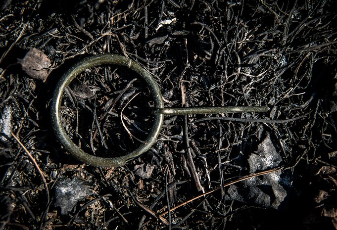 A pin from an M18 smoke grenade lies in the charred grass after it was thrown during a simulated battle during the tactics portion of the Ability to Survive and Operate exercise Jan. 17, 2014, at North Auxiliary Air Field, S.C. The 1st Combat Camera Squadron located at Joint Base Charleston, S.C., hosted the Ability to Survive and Operate Exercise from Jan. 6 through 17. (U.S. Air Force photo/ Senior Airman Dennis Sloan)