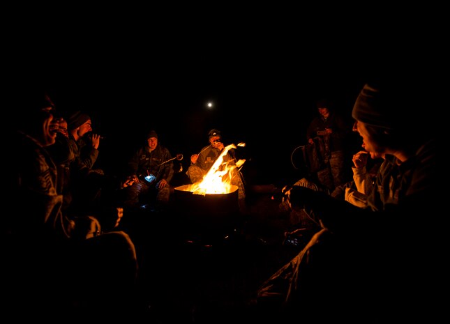 Airmen from the 1st, 2nd and 3rd Combat Camera Squadrons huddle around a fire after completing a full day of tactical training in the field during the Ability to Survive and Operate exercise Jan. 15, 2014, at North Auxiliary Air Field, S.C. The 1st Combat Camera Squadron located at Joint Base Charleston, S.C., hosted the Ability to Survive and Operate Exercise from Jan. 6 through 17. (U.S. Air Force photo/ Senior Airman Dennis Sloan)
