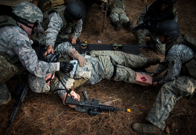 Airmen from the 1st, 2nd and 3rd Combat Camera Squadrons lift an Airman, with simulated injuries to his arms and legs, onto a tactical litter during the Self-Aid Buddy Care portion of the Ability to Survive and Operate exercise Jan. 15, 2014, at North Auxiliary Air Field, S.C. The 1st Combat Camera Squadron located at Joint Base Charleston, S.C., hosted the Ability to Survive and Operate Exercise from Jan. 6 through 17. (U.S. Air Force photo/ Senior Airman Dennis Sloan)