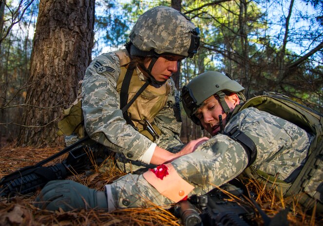 Senior Airman Michelle Di Ciolli, 1st Combat Camera broadcaster, applies a tourniquet to Senior Airman John Raven, 1st CTCS broadcaster, during the Ability to Survive and Operate exercise Jan. 15, 2014, at North Auxiliary Air Field, S.C. The exercise was organized to sharpen Airmen’s skills and their ability to operate as combat documentation specialists outside the wire. (U.S. Air Force photo/ Airman 1st Class Clayton Cupit)