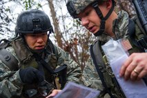 Maj. Mindy Ju, 1st Combat Camera Squadron officer, suggests navigational routes to Senior Airman Gregory Cerny, 1st Combat Camera Squadron broadcaster, during the Ability to Survive and Operate exercise Jan. 14, 2014, at North Auxiliary Air Field, S.C. The exercise was organized to sharpen Airmen’s skills and their ability to operate as combat documentation specialists outside the wire. (U.S. Air Force photo/ Airman 1st Class Clayton Cupit)