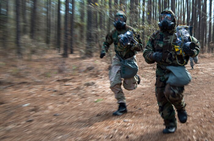 Two combat documentation specialists run between simulated contaminated sites during the Ability to Survive and Operate exercise Jan. 17, 2014, at North Auxiliary Air Field, S.C. The exercise was organized to sharpen Airmen’s skills and their ability to operate as combat documentation specialists outside the wire. (U.S. Air Force photo/ Airman 1st Class Clayton Cupit)