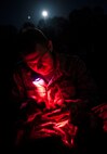 Airman Taylor Queen, 2nd Combat Camera Squadron photojournalist, uses a red light to prevent blinding individuals wearing night vision goggles while preparing food during the night portion of the tactical movement patrol during the Ability to Survive and Operate exercise Jan. 14, 2014, at North Auxiliary Air Field, S.C. The 1st Combat Camera Squadron located at Joint Base Charleston, S.C., hosted the Ability to Survive and Operate Exercise from Jan. 6 through 17. (U.S. Air Force photo/ Senior Airman Dennis Sloan)