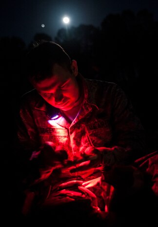 Airman Taylor Queen, 2nd Combat Camera Squadron photojournalist, uses a red light to prevent blinding individuals wearing night vision goggles while preparing food during the night portion of the tactical movement patrol during the Ability to Survive and Operate exercise Jan. 14, 2014, at North Auxiliary Air Field, S.C. The 1st Combat Camera Squadron located at Joint Base Charleston, S.C., hosted the Ability to Survive and Operate Exercise from Jan. 6 through 17. (U.S. Air Force photo/ Senior Airman Dennis Sloan)