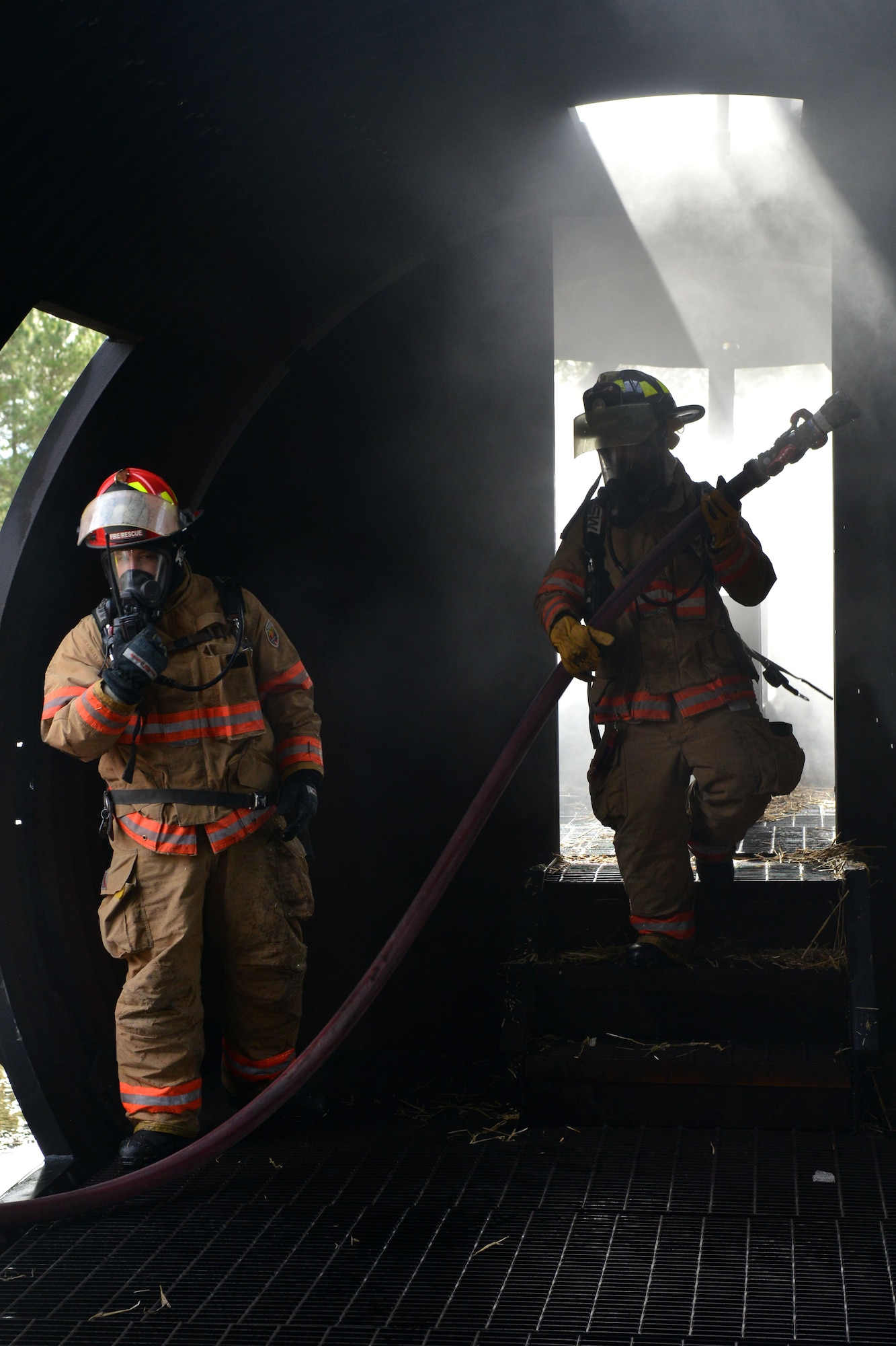 [From left] U.S. Air Force Staff Sgt. Darin Meek, 20th Civil Engineer Squadron firefighter and Senior Airman Brandon Young, 20th Civil Engineer Squadron firefighter walk away from the front of a plane after putting out a fire, Shaw Air Force Base, S.C., Jan. 13, 2014. The Airmen put out a fire as a part of training for one of their exercises they had to participate in. (U.S. Air Force photo by Senior Airman Ashley L. Gardner/Released)