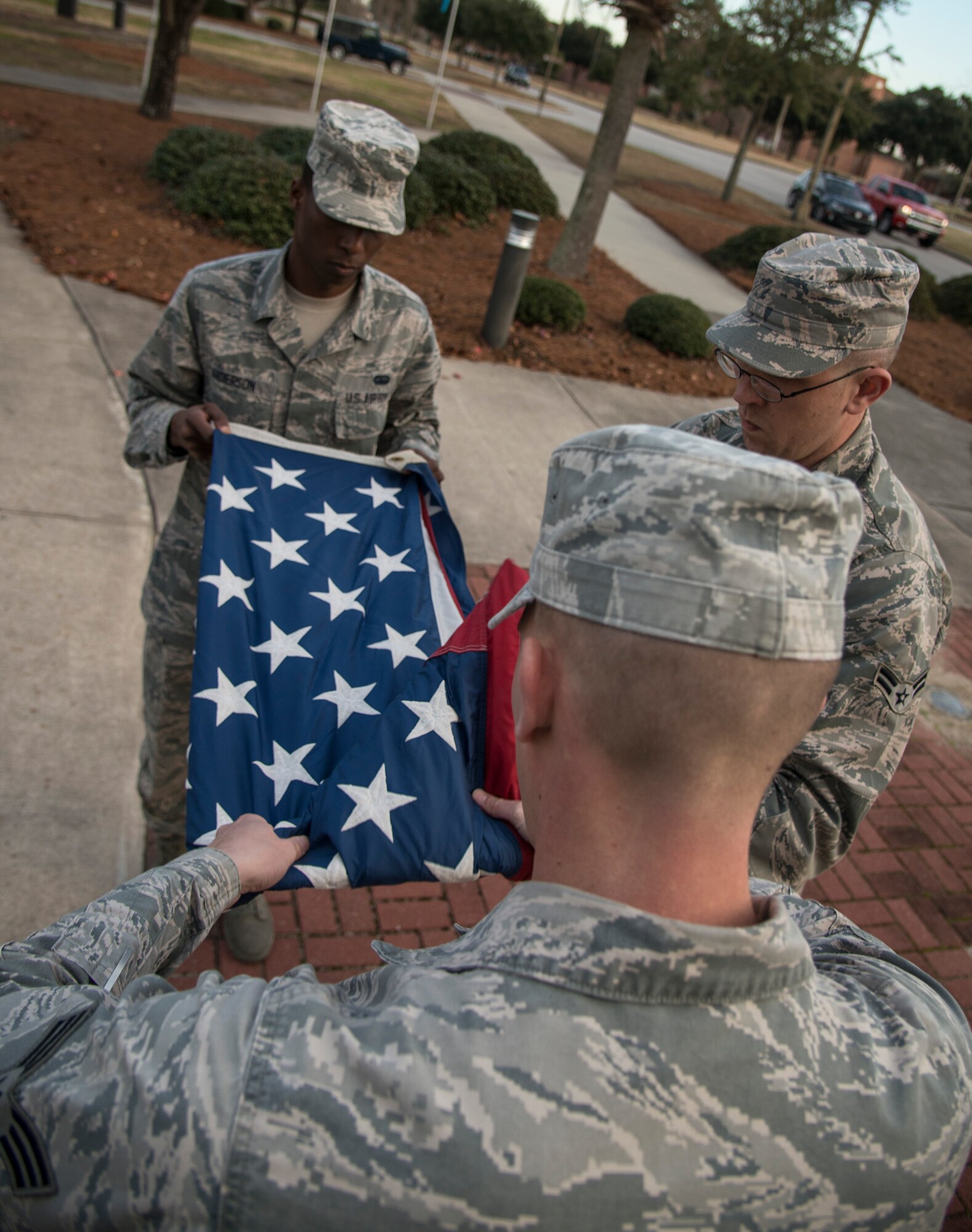 From left to right, Airmen 1st Class Robert Andersen,  Joshua Westbrook, and Senior Airman Robert Wessinger fold the flag during a retreat ceremony Jan. 21, 2014, at Joint Base Charleston - Air Base, S.C. During retreat, a two-man fold is conducted after the playing of the national anthem, with the NCO of the detail under watch. After it is meticulously folded into its final form the flight commander orders the colors to be retired, signifying the end of the duty day. Amos, Westbrook, and Wessinger are members of the 628th Communications Squadron.  (U.S. Air Force photo/Tech. Sgt. Rasheen Douglas)