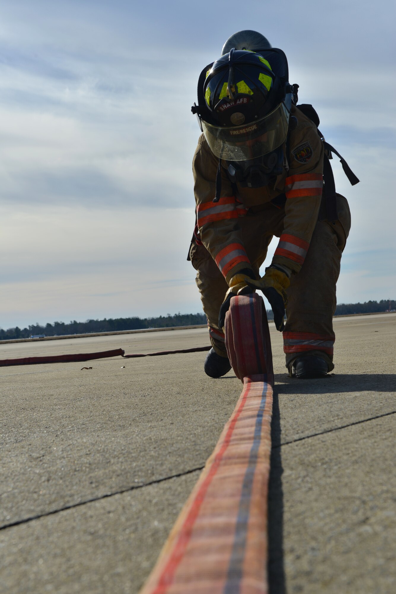 U.S. Air Force Senior Airman Brandon Young, 20th Civil Engineer Squadron firefighter, rolls up a fire hose on the flight line at Shaw Air Force Base, S.C., Jan. 13, 2014.  Young, along with several other firefighters, was participating in an operational readiness exercise and had just finished an aircrew extraction exercise, which prepares them to properly rescue pilots in the event that they are trapped in an aircraft. (U.S. Air Force photo by Airman 1st Class Jensen Stidham/Released)