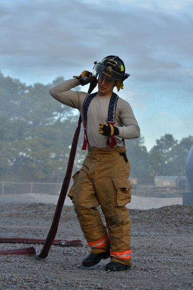 U.S. Air Force Airman 1st Class Clayton Angleoff, 20th Civil Engineer Squadron firefighter, drags a fire hose at Shaw Air Force Base, S.C., Jan. 13, 2014. Angleoff had just finished extinguishing a controlled aircraft fire as part of training during an operational readiness exercise. (U.S. Air Force photo by Airman 1st Class Jensen Stidham/Released) 