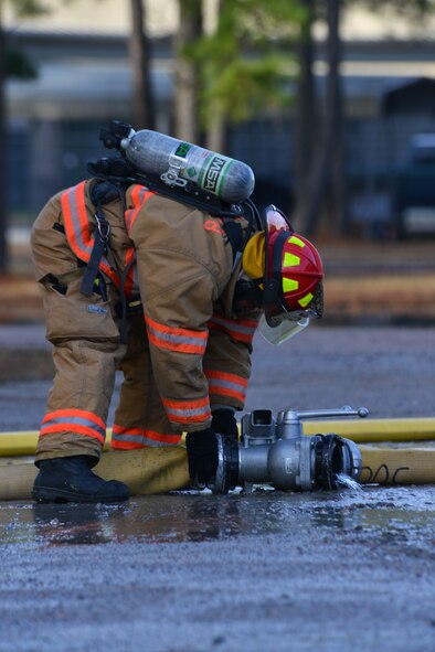 U.S. Air Force Staff Sgt. Patrick Bentley, 20th Civil Engineer Squadron firefighter, disconnects a water manifold at Shaw Air Force Base, S.C., Jan. 13, 2014. Bentley had just finished extinguishing a controlled aircraft fire as part of training during an operational readiness exercise. (U.S. Air Force photo by Airman 1st Class Jensen Stidham/Released)